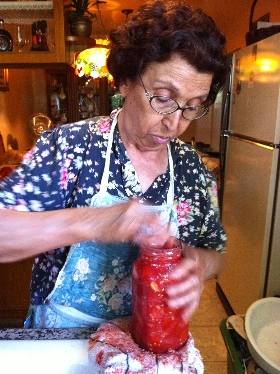 Mel's Nonna placing tomatoes in a jar in her small kitchen